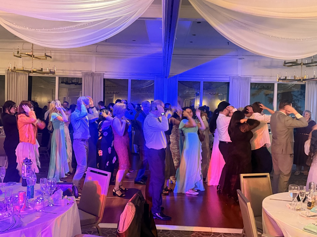 Guests dancing together under purple and blue lighting at a reception