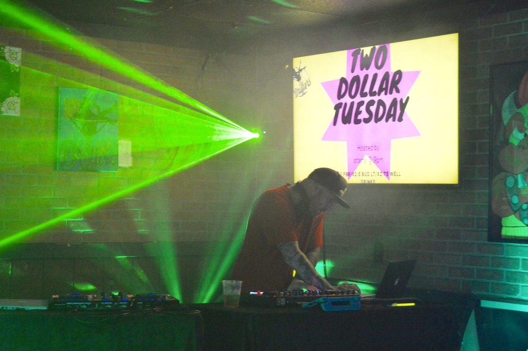 DJ Ravick performing with green laser lighting across the room