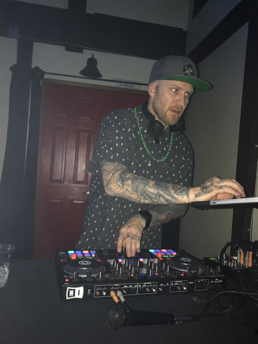 DJ Ravick working at his controller with headphones around his neck